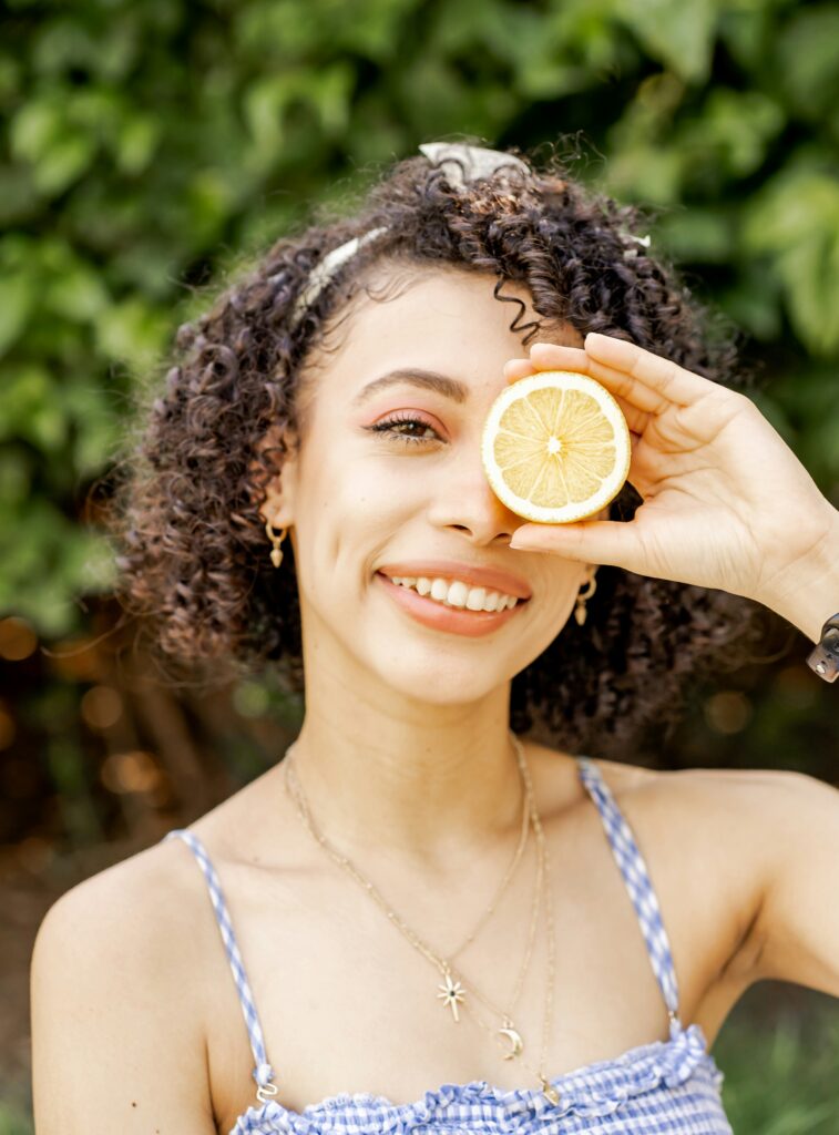 a girl is putting a piece of lemon on front of her left eye 